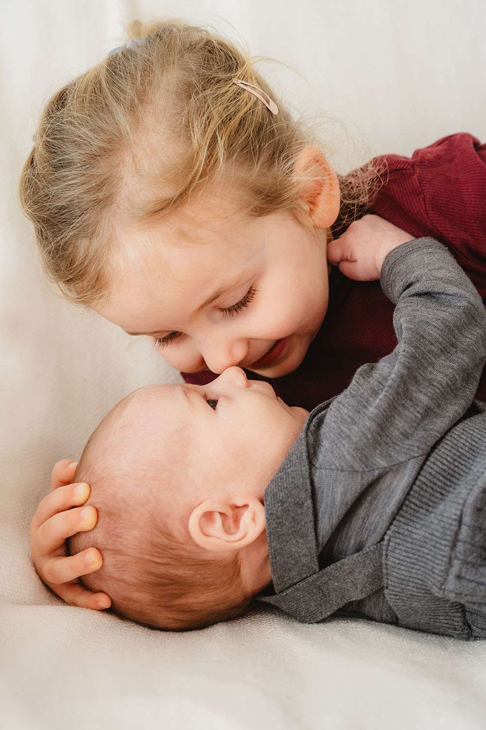 Schwester gibt Baby eine Kuss bei einem Newborn Shooting bei Mannheim