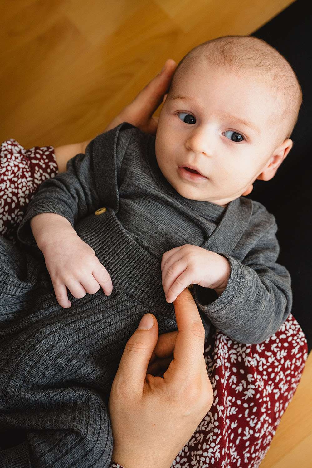 Baby liegt bei der Mutter und hält ihren Finger fest