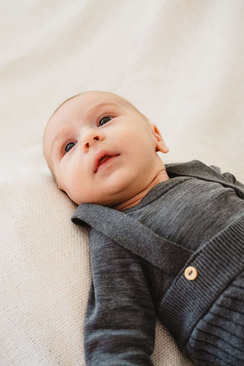 Newborn liegt auf einem Kissen und schaut nach oben