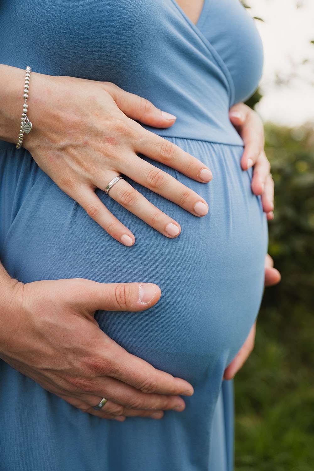 Hände liegen auf einem Babybauch