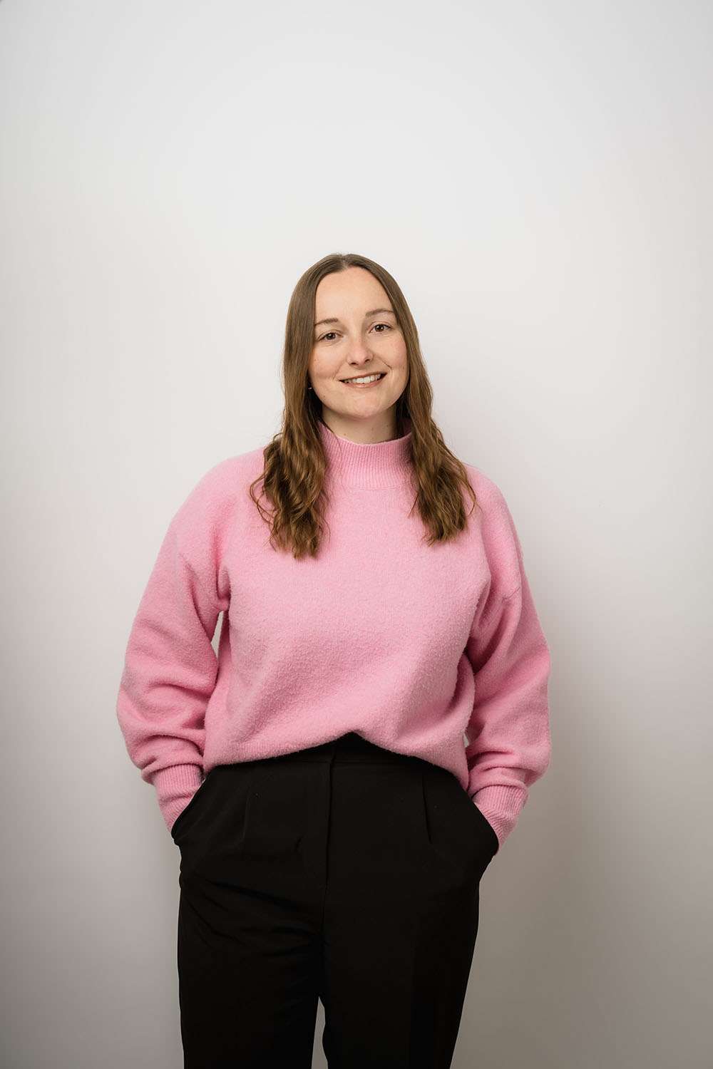 Frau mit pinken Pulli fotografiert in einem Fotostudio