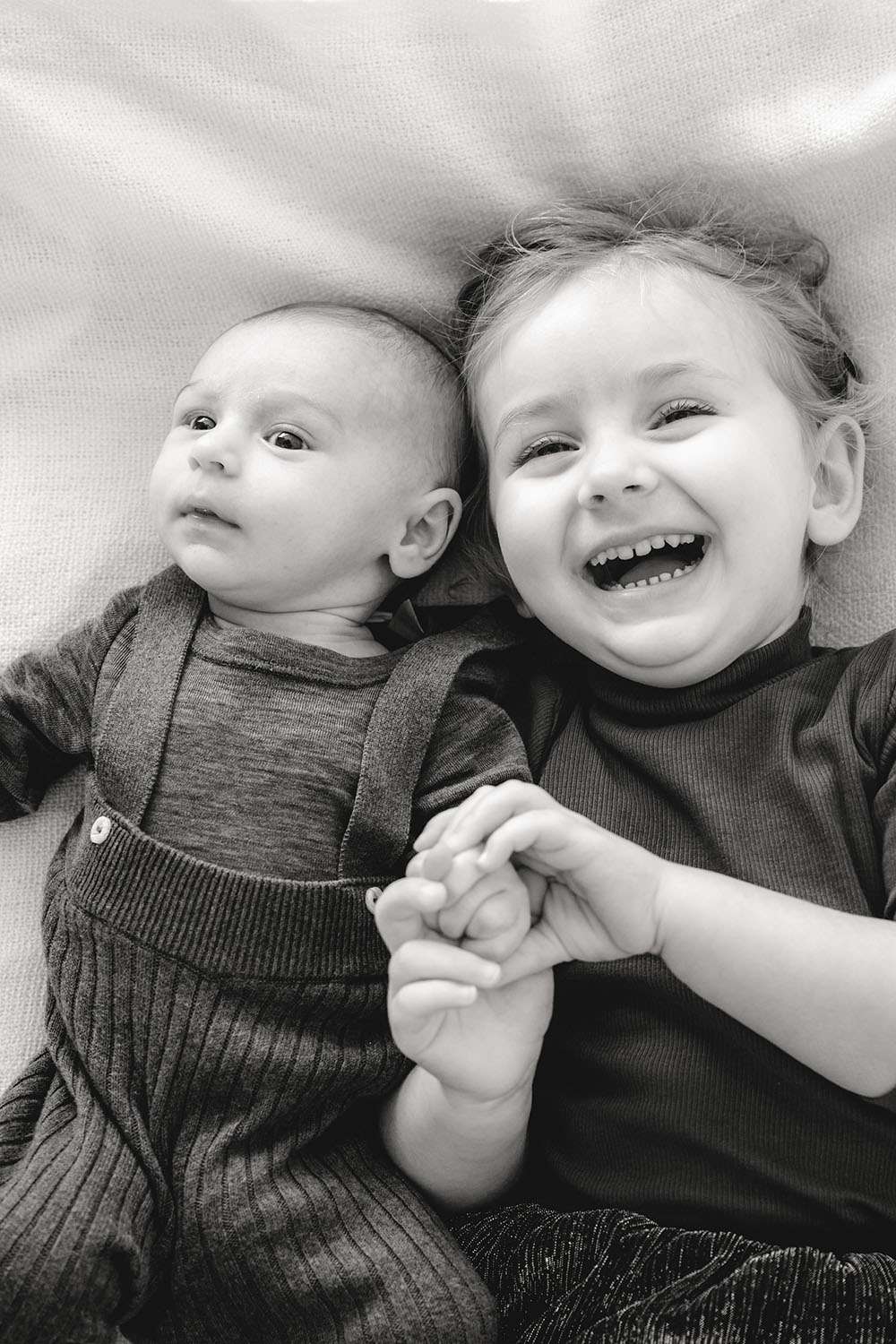 Schwarz Weiß Foto von einem Neugeborenem und seiner lachenden Schwester