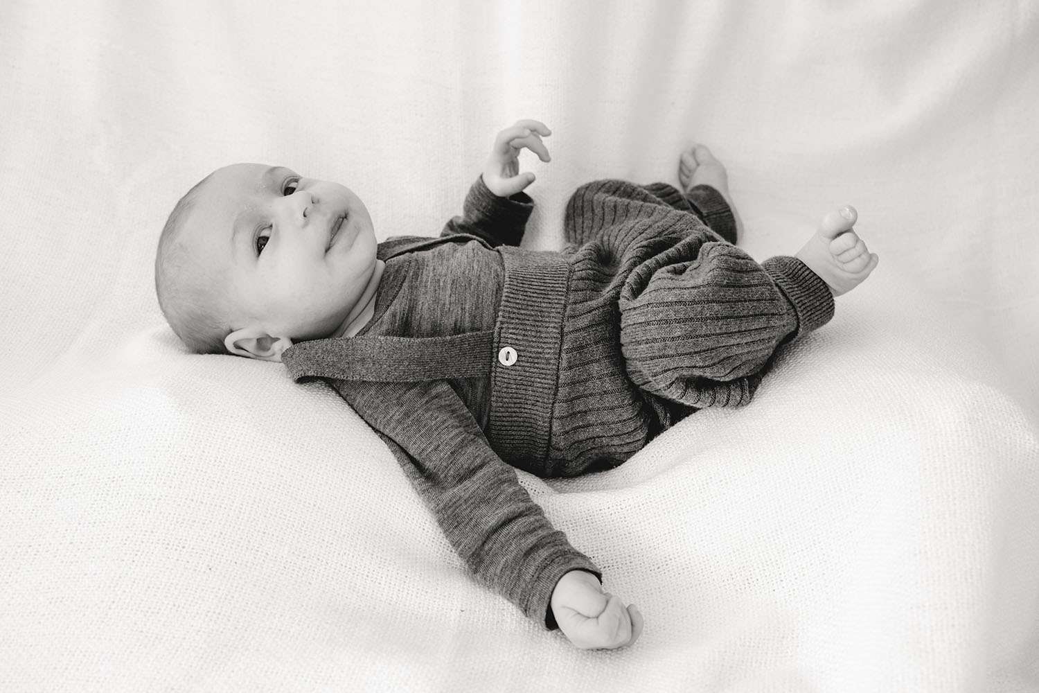 Baby liegt auf dem Rücken fotografiert in Schwarz Weiß