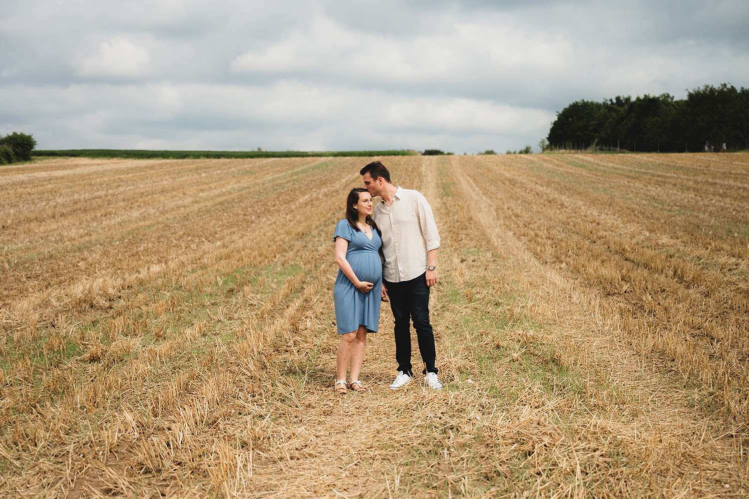 Schwangere Frau und ihr Mann stehen auf einem Feld