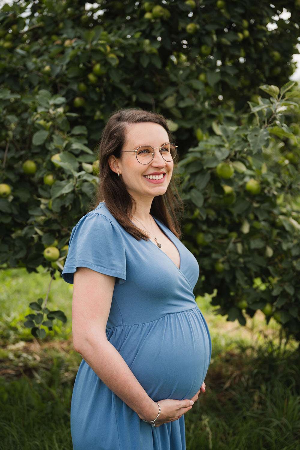 Frau mit Babybauch blickt in die Ferne und lacht