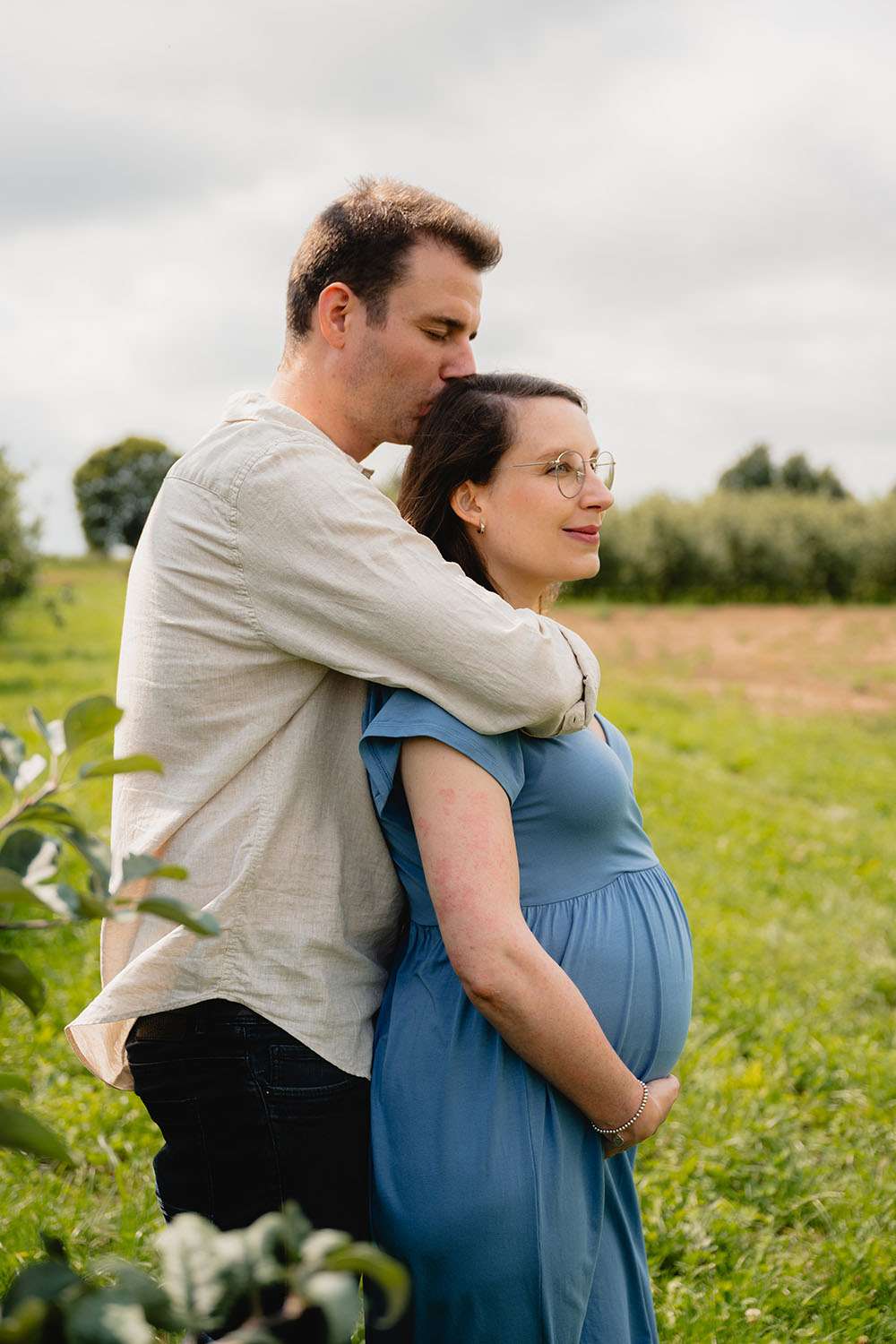 Frau mir Babybauch wird von ihrem Mann umarmt