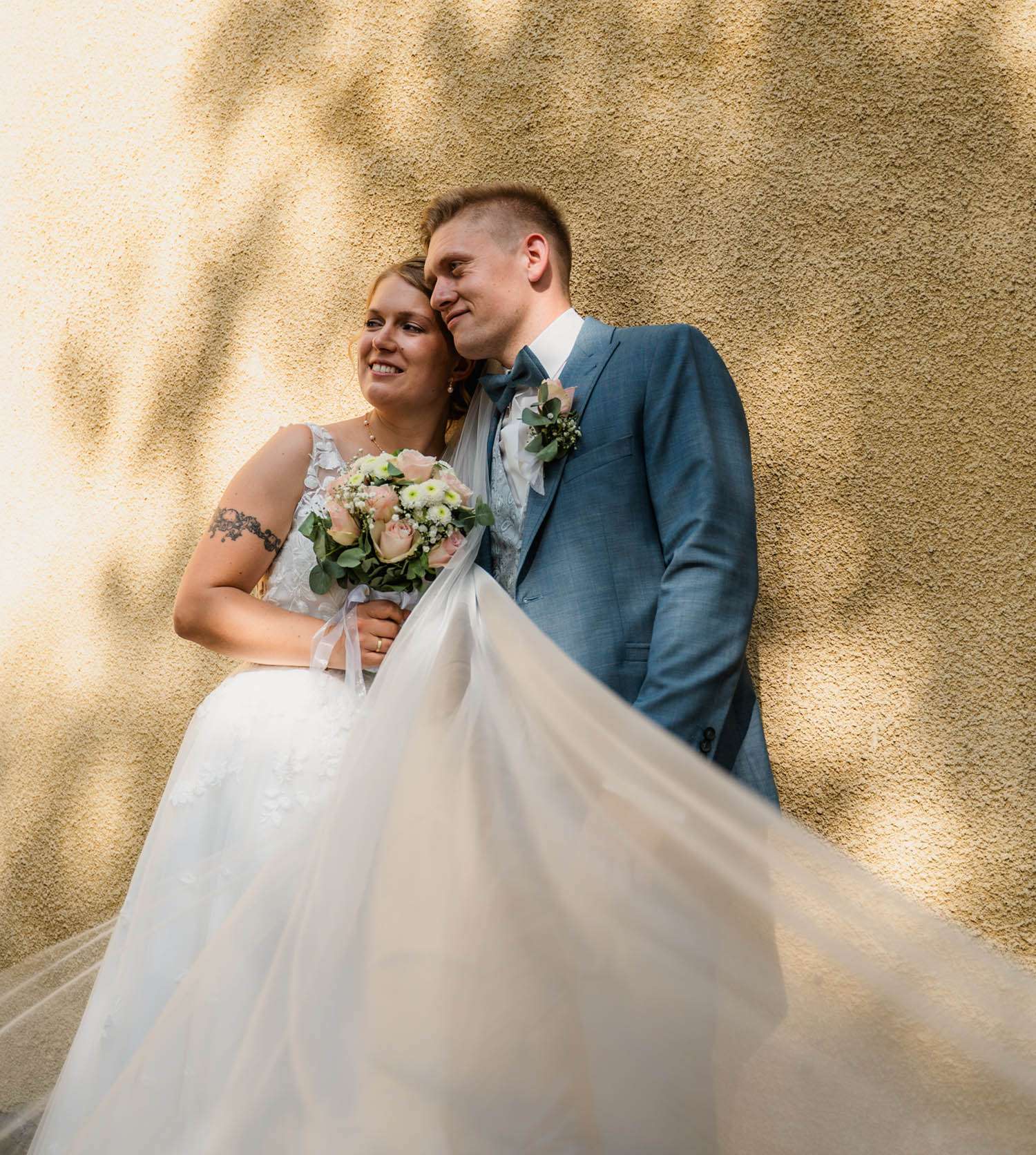 Glückliches Brautpaar steht im Sonnenlicht im Weinheimer Schlosspark