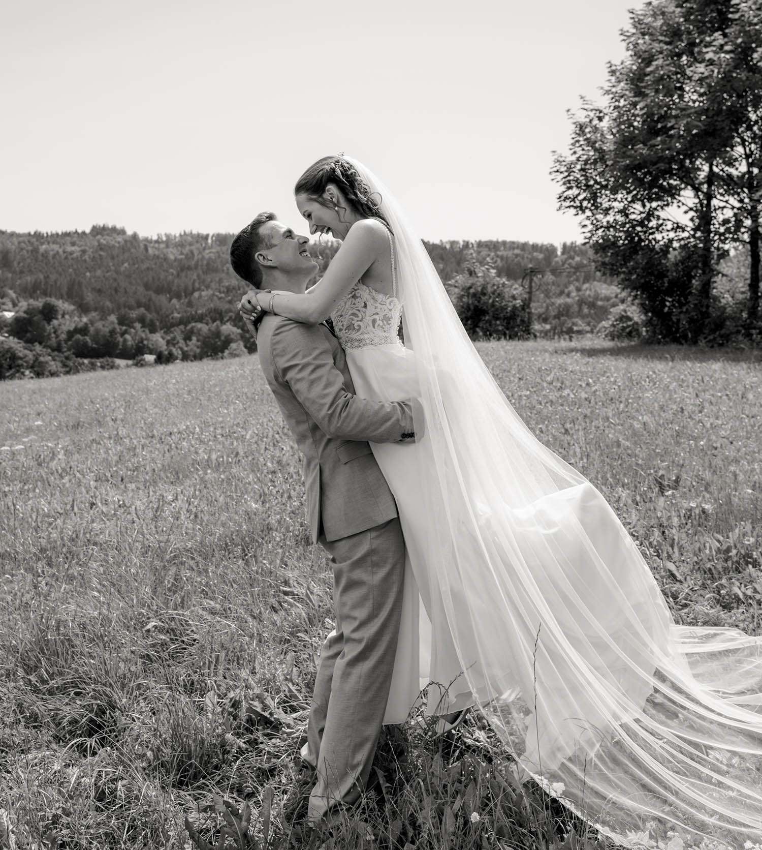 Bräutigam hebt die Braut in die Luft fotografiert in schwarz-weiß