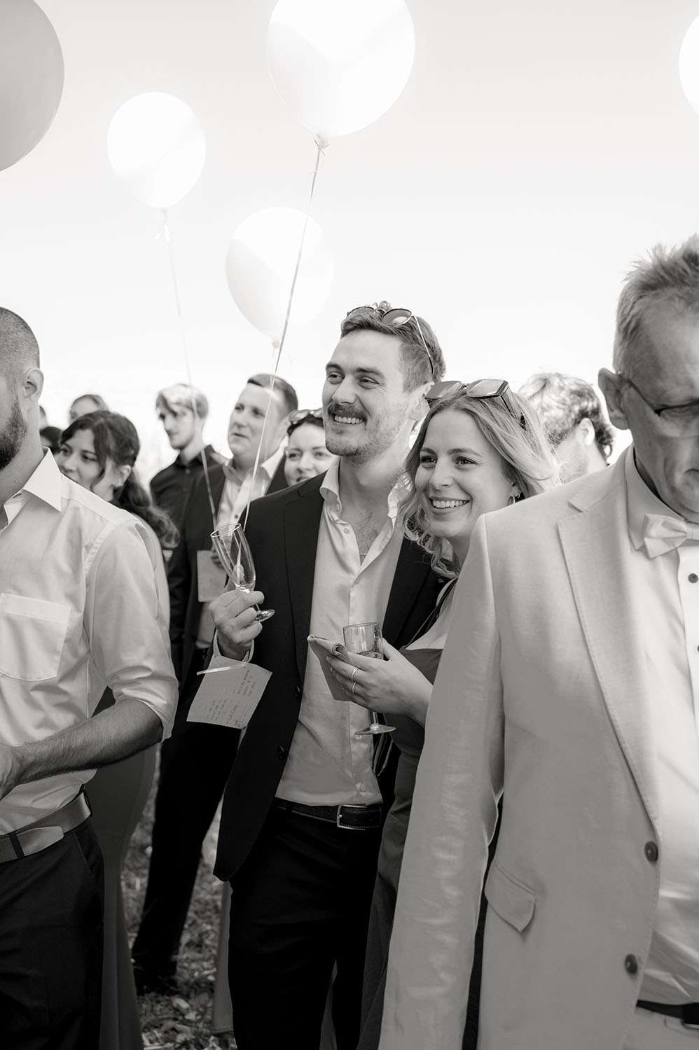 Lachende Gäste mit Ballon bei einer Sommerhochzeit