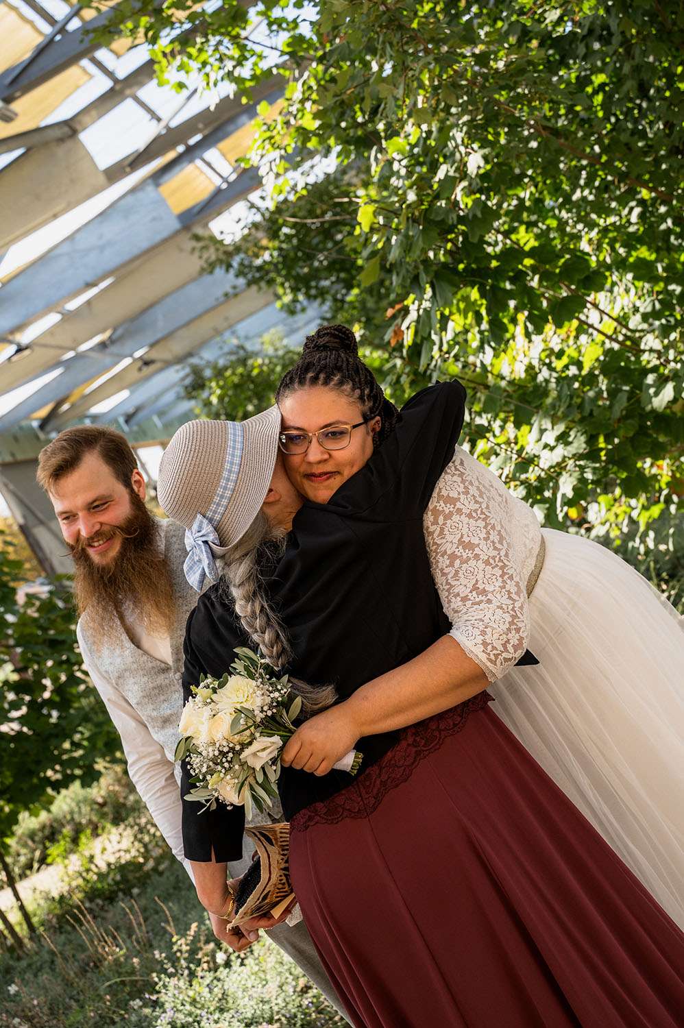 Braut umarmt Frau mit Hut