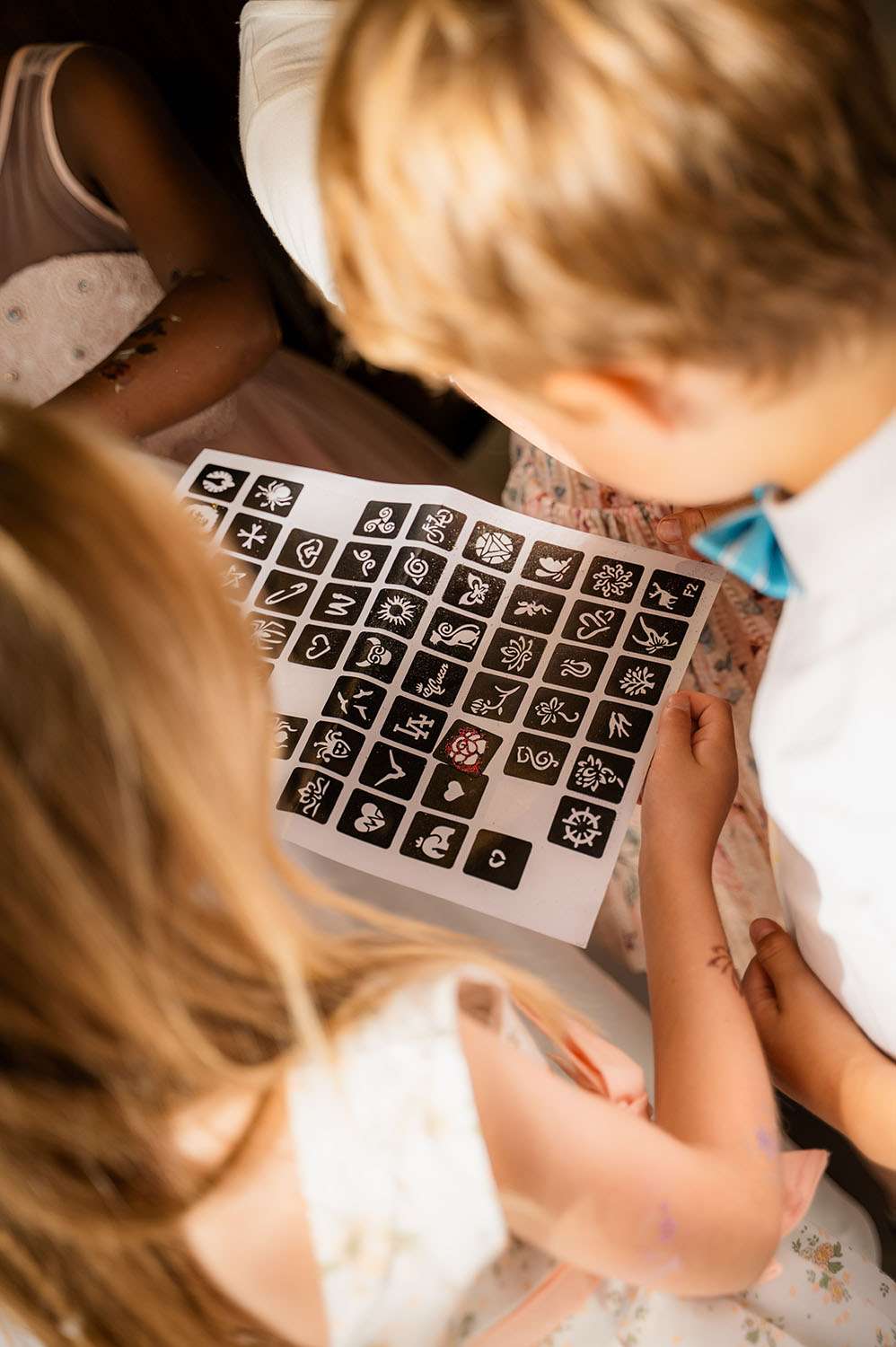Kinder schauen sich Klebetattoos an