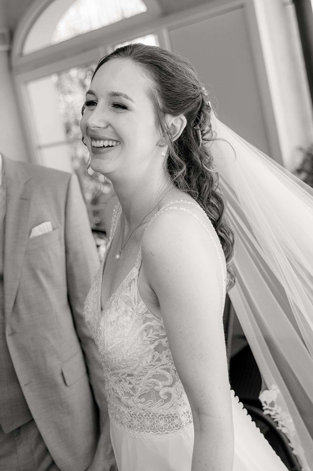 Braut lacht bei First Look fotografiert in schwarz-weiß