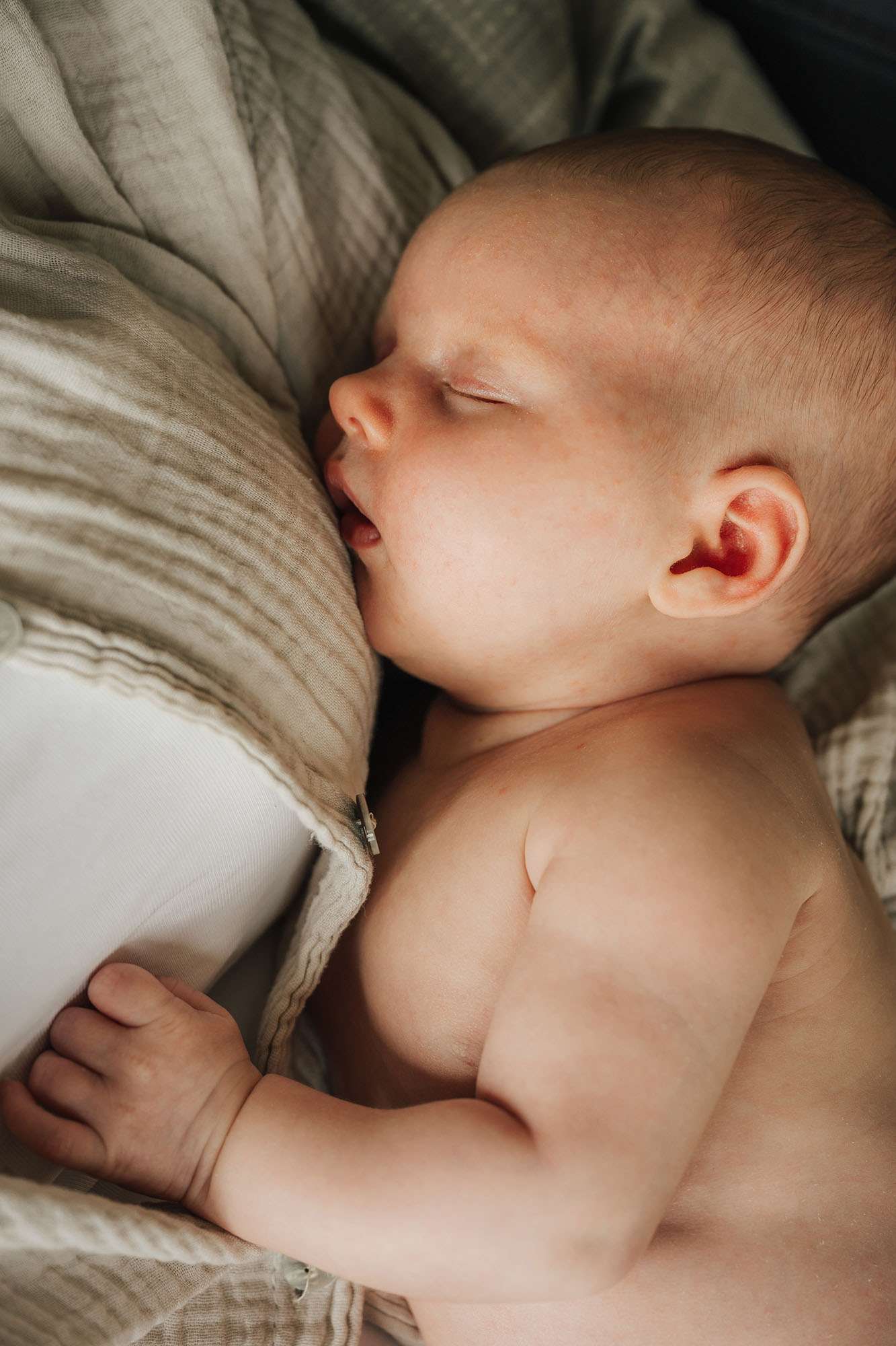 Schlafendes Baby liegt im Arm der Mutter