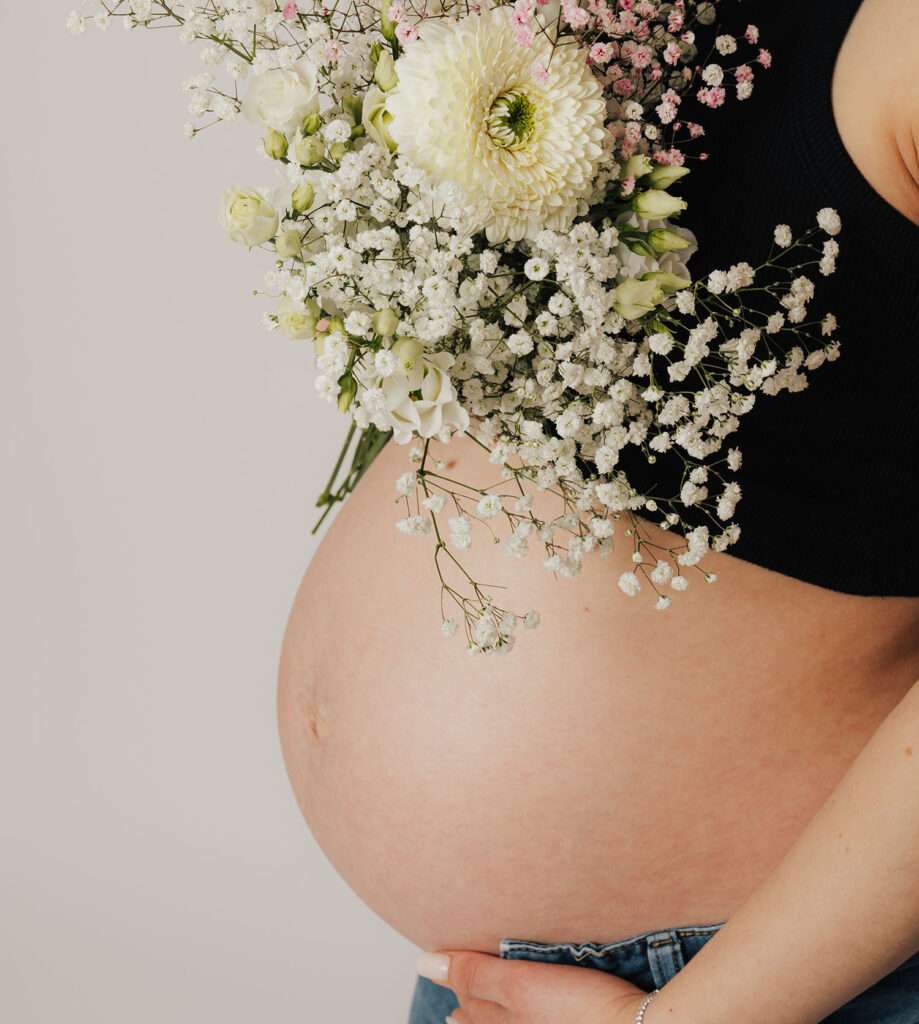 Detailfoto vom Babybauch mit Blumen